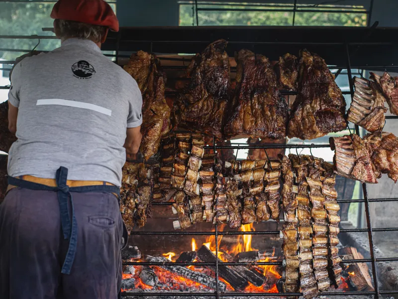 Chef bereidt vlees op de Argentijnse parrilla grill bij San Thomas